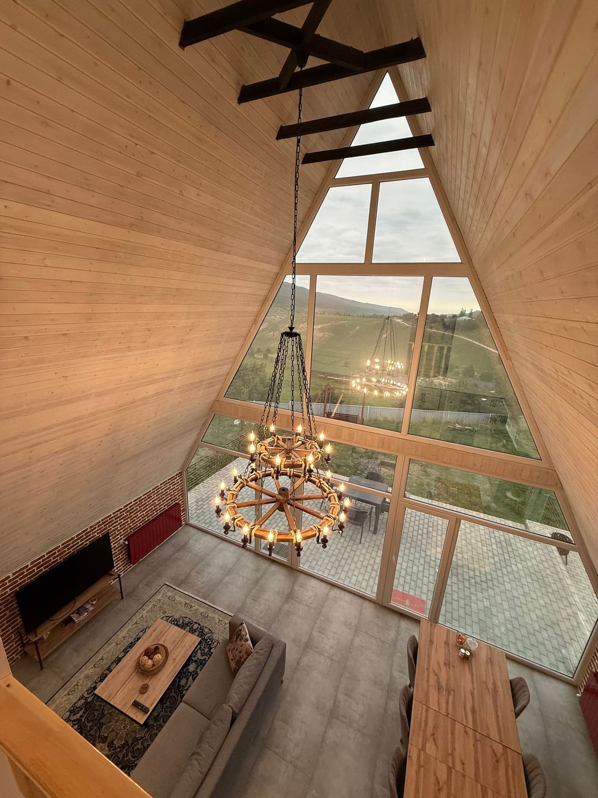 Living room with a high vaulted timber ceiling and triangular window, seen from above