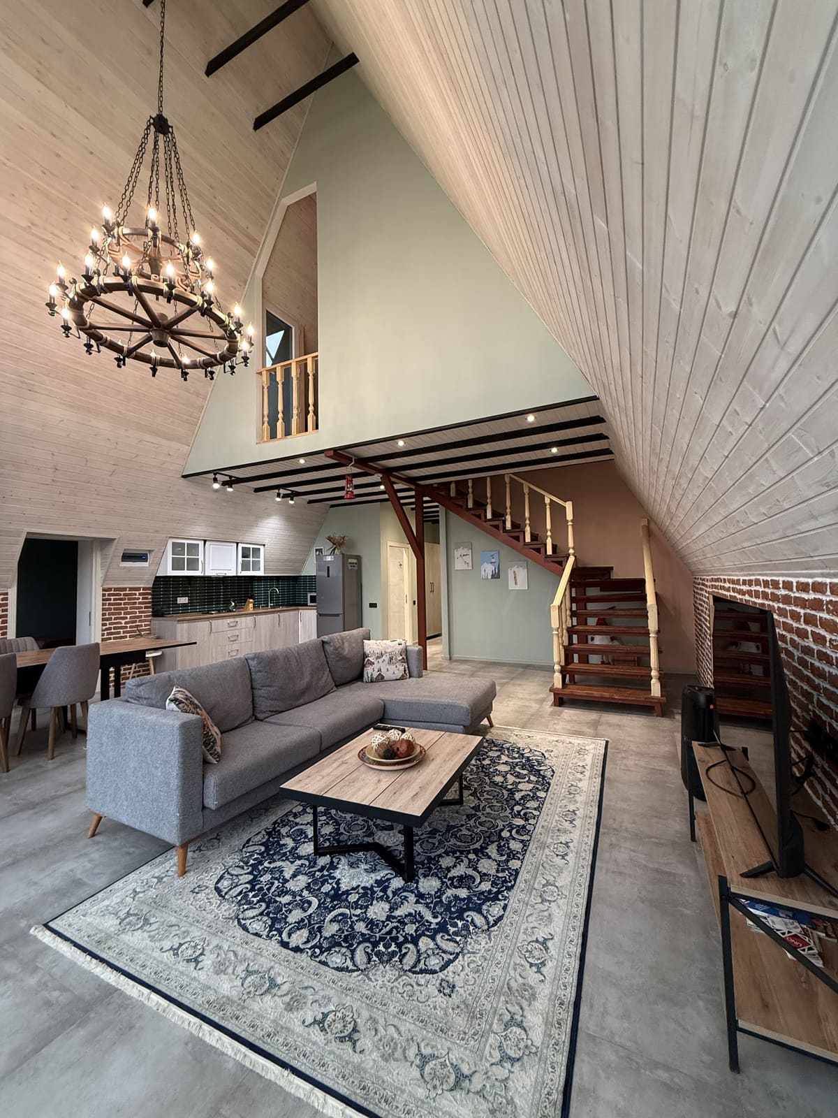 Living room with a corner sofa and rug, stairs to the upper level and the kitchen at the back