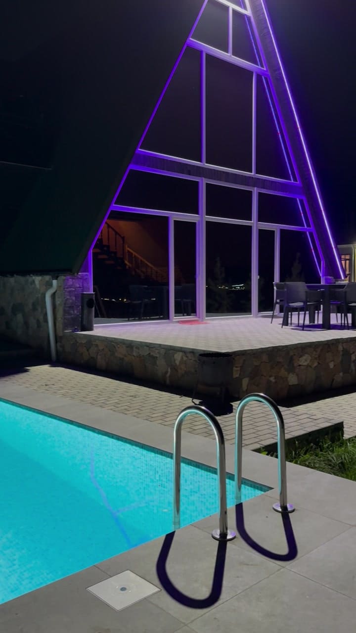 The illuminated triangular facade and the glowing pool at night