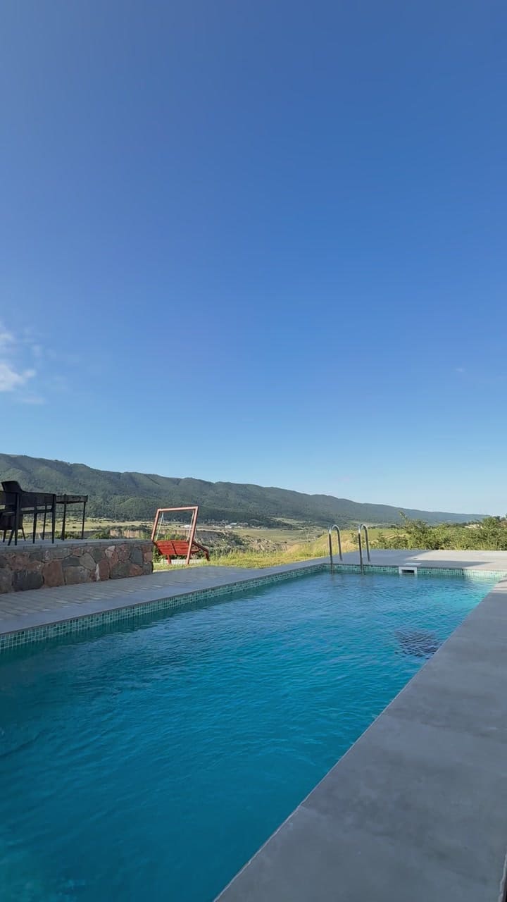 A long outdoor pool with turquoise water, mountains on the horizon under a clear sky