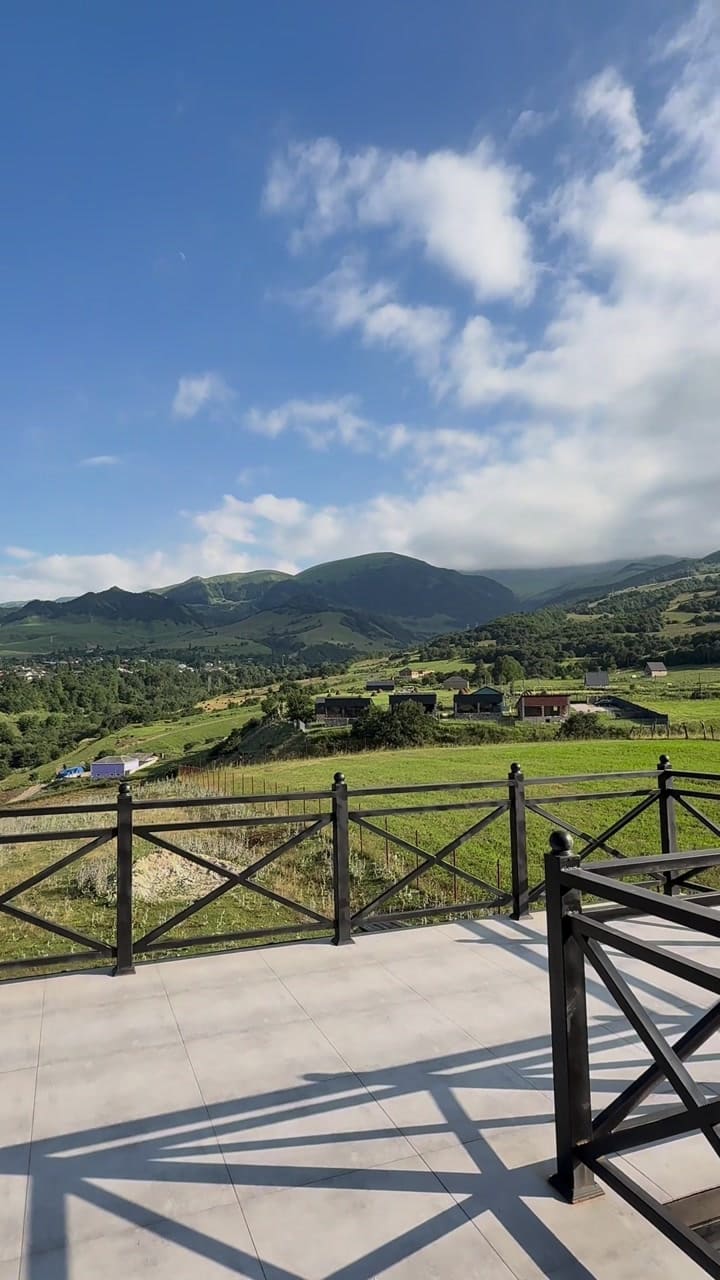 View from the terrace across a green valley to the mountains
